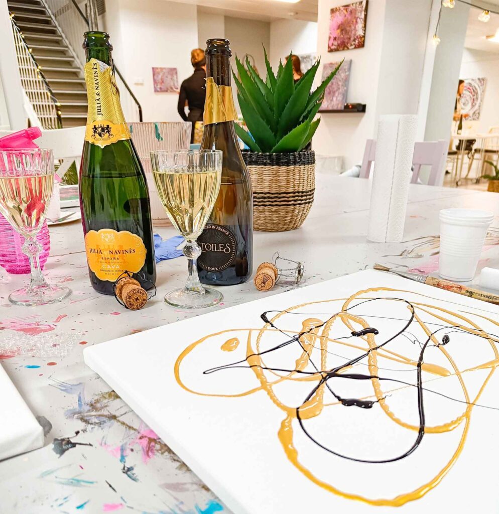Kuvassa viinipullot ja lasit, jotka ovat ateljeen pöydällä. Paint and wine